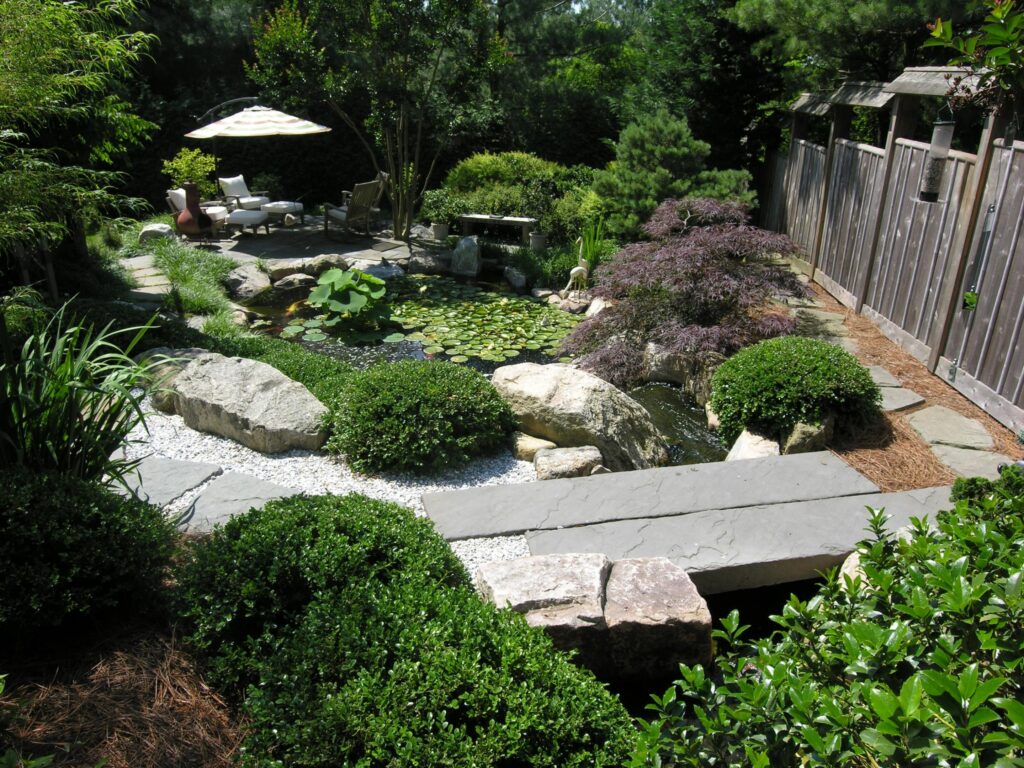 Custom Stone Bridge Crosses Stream Above Koi Pond With Lotus And Waterlilies, Wyomissing, Pa