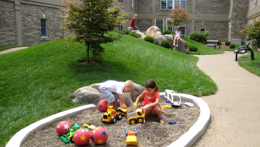 Children Enjoy A Simple Playground Of Grassy Hills Surrounded By A Tricycle Path, In The Safety Of An Enclosed Pre-School Courtyard, Lancaster, Pa